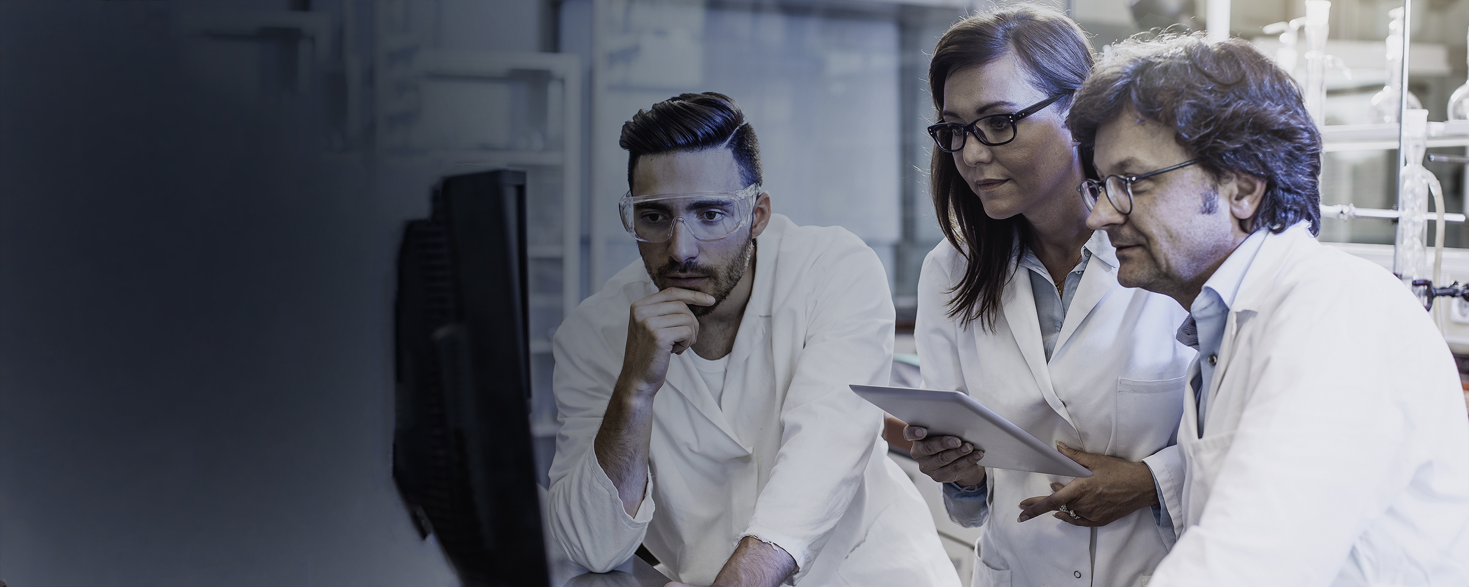 Three scientists viewing a monitor